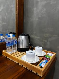 a wooden tray with two cups and bottles of water at Paris Garden Resort in Trincomalee