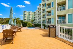 a deck with chairs and umbrellas in front of a building at Sands Beach Club in Myrtle Beach