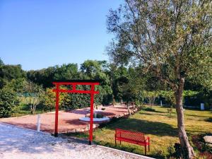 a red structure in a park with a bench at As Cabanas DO RÍO PEGO in Santiago de Compostela