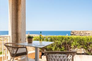 a table with wine glasses on a balcony with the ocean at VORAMAR by 3VILLAS in Cala en Forcat