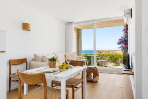 a living room with a table and chairs with a view of the ocean at VORAMAR by 3VILLAS in Cala en Forcat
