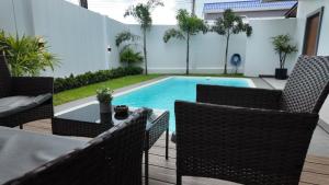 a swimming pool with chairs and a table in a backyard at Zoha 2BR Private Pool Villa Bangtao in Thalang