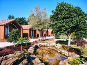 a garden with a pond in front of a house at As Cabanas DO RÍO PEGO in Santiago de Compostela