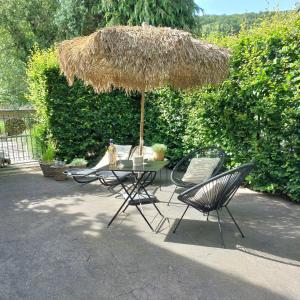 a table and two chairs under a straw umbrella at Le Grenier in Trois-Ponts
