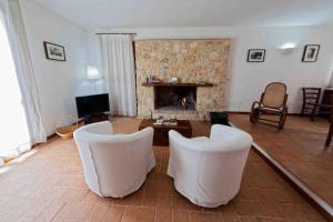 uma sala de estar com cadeiras brancas e uma lareira em La Perticara Agriturismo em Acquasparta
