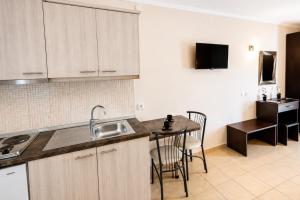 a kitchen with a sink and a table with chairs at Studios Plaka in Skala Kallirachis