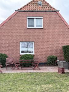 a red brick house with two benches and a window at Ferienwohnung am Binnensee 2 in Heiligenhafen
