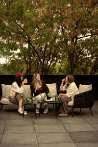three women sitting on benches eating and drinking at Boga Mexico City by Lumina in Mexico City