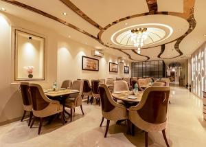 a restaurant with tables and chairs and a chandelier at Hotel The Venue At Delhi Airport IGI in New Delhi