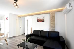 a living room with a black couch and a table at LEMON GARDEN Playa in Puerto de Sagunto