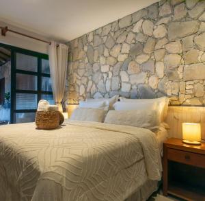 a bedroom with a large bed with a stone wall at Villa Meraki in Pipa +152 photos