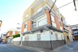 a white building with a balcony on a street at LEMON GARDEN Playa in Puerto de Sagunto