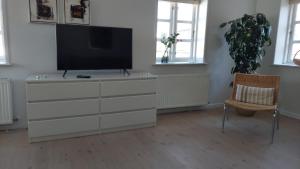 a living room with a television and a chair at Tversted Strandkro in Bindslev