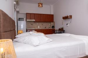 a bedroom with a white bed and a kitchen at Theahouse in Pythagoreio