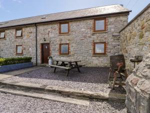 a stone house with a picnic table in front of it at Stabal-y-Gwedd in Llanddulas