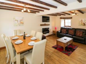 a dining room and living room with a table and chairs at Stabal-y-Gwedd in Llanddulas