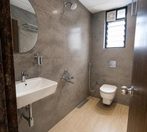 a bathroom with a sink and a toilet and a mirror at Hotel Pune Grand in Pune