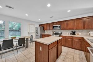 una cucina con mobili in legno, tavolo e sedie di Drifting Shadows a Conroe Altre 30 foto
