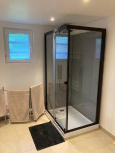 a glass shower in a room with two chairs at Au Petit Paradis in Balan