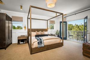 a bedroom with a canopy bed and a balcony at Polo House and Bungalows in Santa Ynez