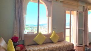 a couch with pillows in a room with a window at Indigo House in Chefchaouen