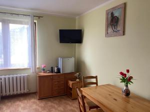 a living room with a table and a television on the wall at Rozalia in Stary Borek