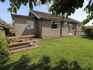 a house with a picnic bench in the yard at Llwyn Eithin in Benllech