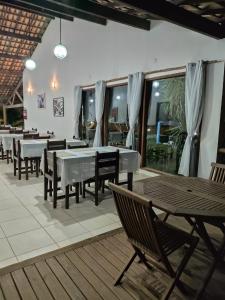 a restaurant with tables and chairs and windows at Pousada Lagoa Da Pedra in Imbassai