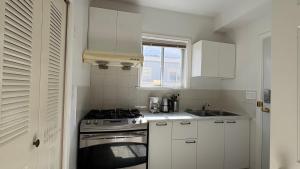 a white kitchen with a stove and a sink at Richmond Cozy Place 2 in Richmond