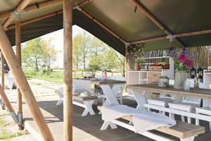 a wooden pavilion with a table and benches at Smuk Grutte Bell Tent nabij het water in Friesland in Echtenerbrug