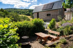a garden with a bench and a house with solar panels at Taunus Tinyhouse - Sauna, Grillplatz & Naturidylle in Weilrod