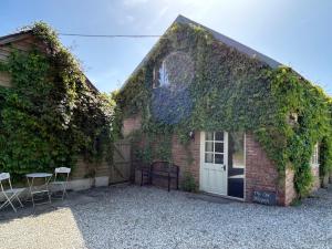 an ivy covered house with two chairs and a door at The Old Shippen, Drewsteignton in Exeter