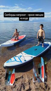 two people are standing on surfboards on the beach at Тайыз Кол in Tossor