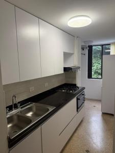 a kitchen with white cabinets and a sink and a refrigerator at We Rent VIP - San Julián in Medellín