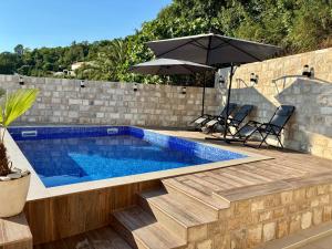 a swimming pool with an umbrella next to a brick wall at Vila Marbela in Seoca