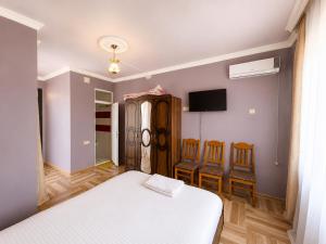 a bedroom with a bed and chairs and a tv at Beliy Dom in Kvariati