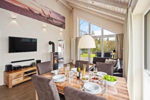 a dining room with a table and chairs and a television at Luxuswellnesshaus Ostwind in Bliesdorf