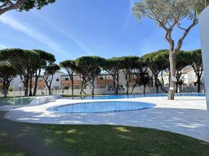 a swimming pool in the middle of a park with trees at Los Pescadores Playa Sol in Novo Sancti Petri