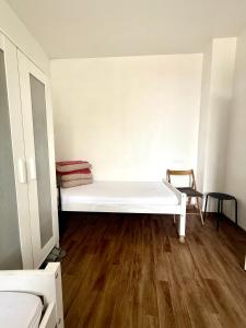 a white bed in a room with a wooden floor at paris kiffe in Villejuif +3 photos