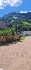 a brick driveway with a fence in front of a mountain at Apartments Pr'Krštano in Kranjska Gora