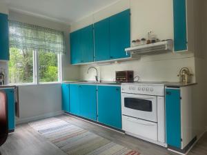a kitchen with blue cabinets and a white stove top oven at Retro hus in Kosta