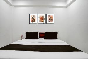 a white bedroom with a bed with three pictures on the wall at Hotel O rudra paradise in New Delhi