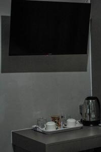 a table with a tv on the wall with cups and dishes at La Palma Suites Guest House in Mochudi +18 photos