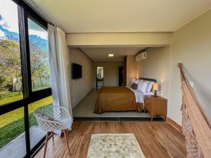 a bedroom with a bed and a large window at Casa do Valle Hotel Boutique - Vale do Capão in Vale do Capao