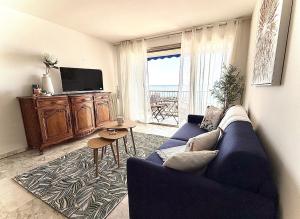 a living room with a blue couch and a tv at Rives dor 1C in Juan-les-Pins