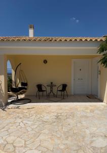a patio with chairs and a table in a house at The Lookout by Goutos Luxury Living in Rozaíika