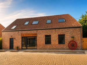 a red brick building with a red roof at VinOli Holiday Home in Alveringem