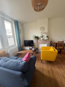 a living room with a blue couch and a yellow chair at Les chtis voyageurs appartement 2 chambres terrasse in Marcq-en-Baroeul