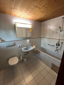 a bathroom with a sink and a toilet and a tub at Bergsteiger-Zimmer Pension Obermair in Mayrhofen