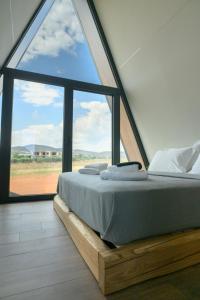 a bed in a room with a large window at Trilogy Resorts in Alexandroupoli